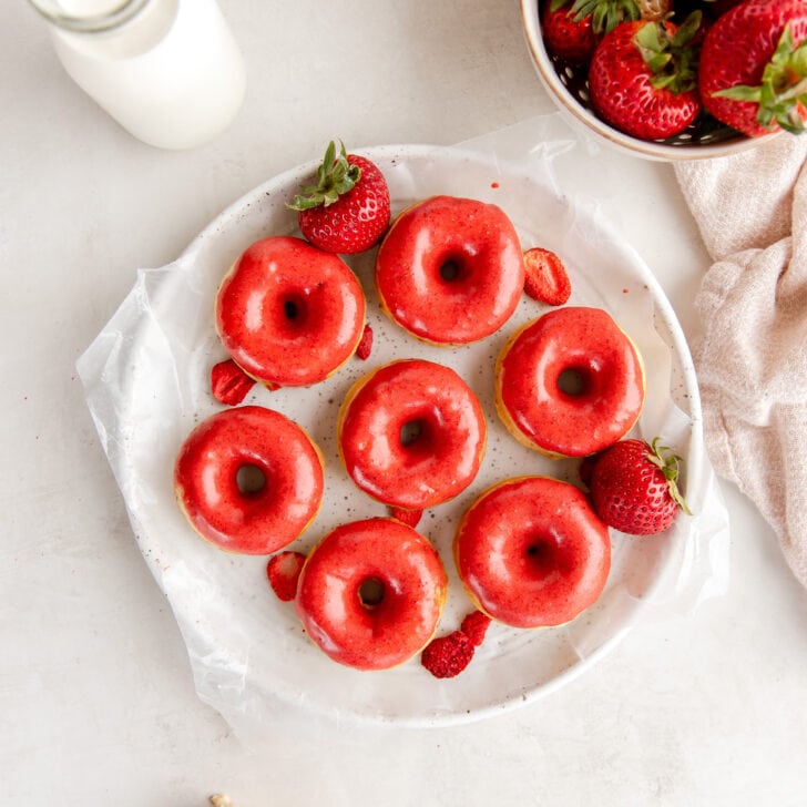 plate of strawberry donuts with bright red icing