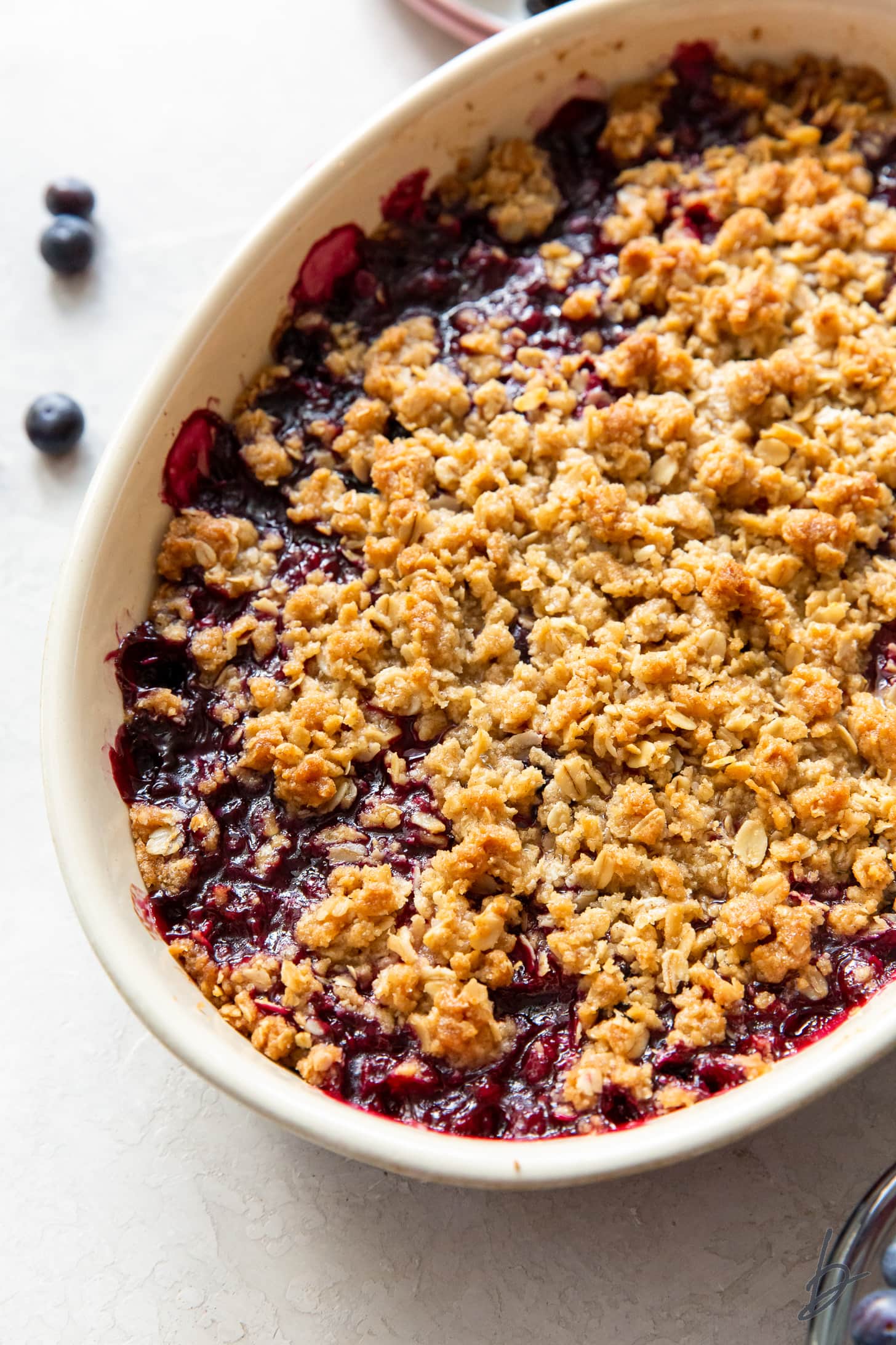 triple berry crisp in oval baking dish with golden oat crisp topping