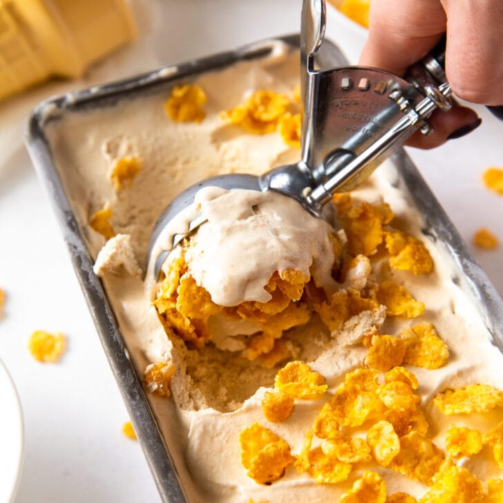 ice cream scoop taking scoop of cereal milk ice cream with cornflakes out of loaf pan