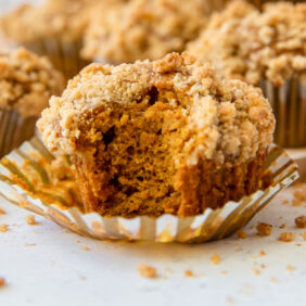 pumpkin muffin with a bite taken out on top of a paper liner