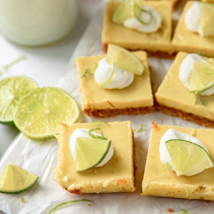 key lime pie bars in squares garnished with whipped cream and lime slices