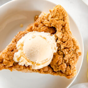 plate with slice of apple crumble pie topped with a scoop of vanilla ice cream