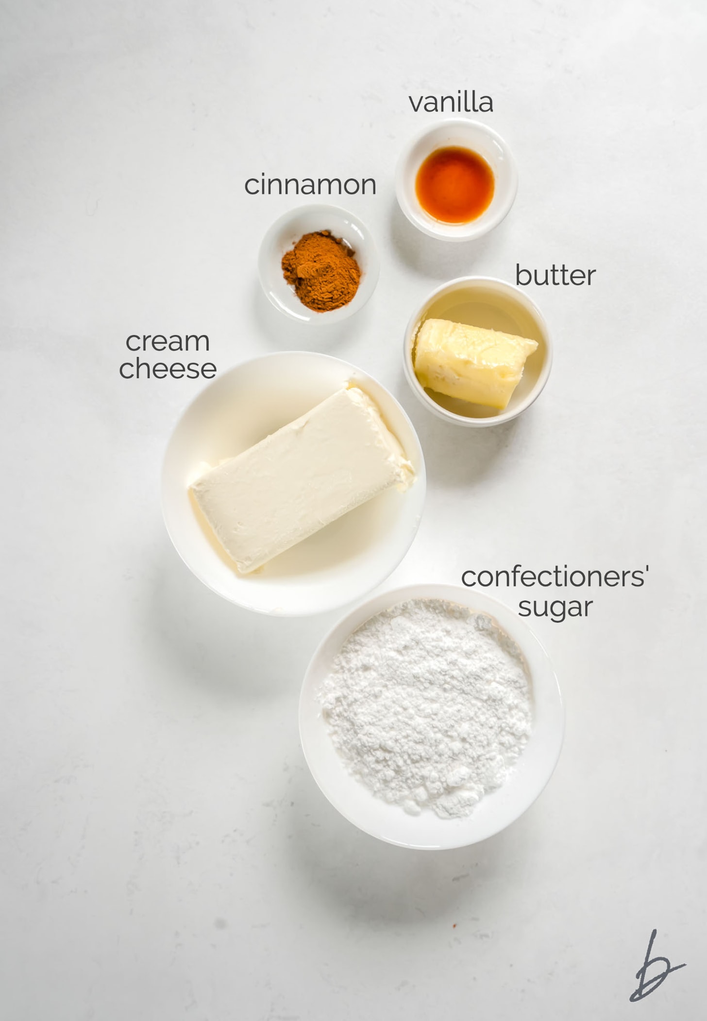 cinnamon cream cheese frosting ingredients in bowls labeled with text