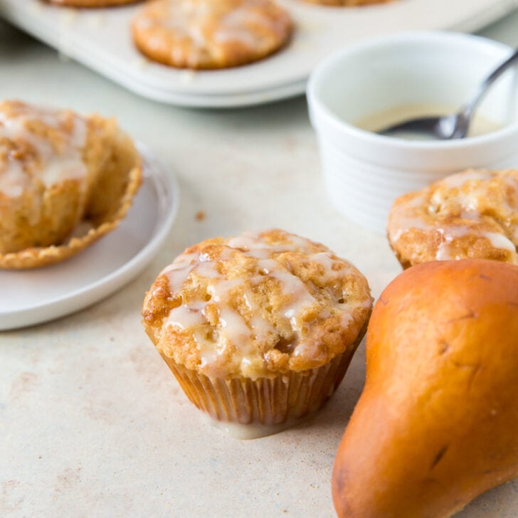 ginger pear muffins with glaze next to brown pear and another muffin