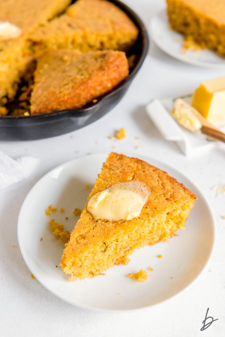 white round plate with triangle slice slice of jalapeno cornbread with melted butter on top