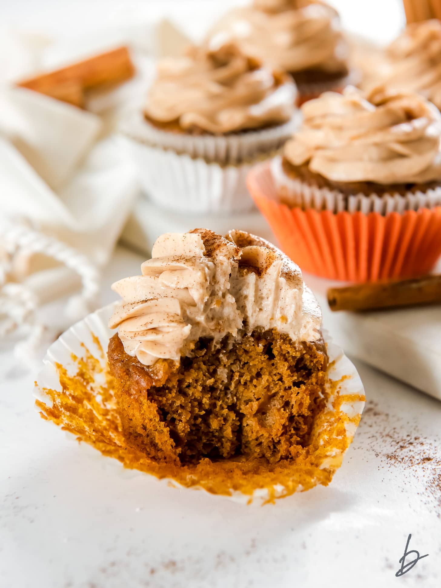 open paper liner with pumpkin cupcake with a bite taken out of it