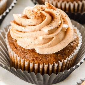 pumpkin cupcake with cinnamon cream cheese frosting on open paper liner