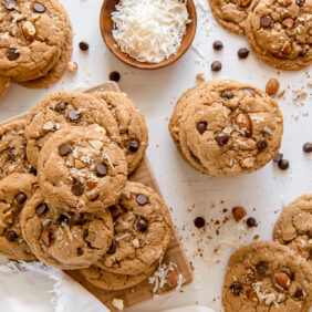 white wood surface with almond butter cookies, pinch bowl with shredded coconut and glass milk bottle