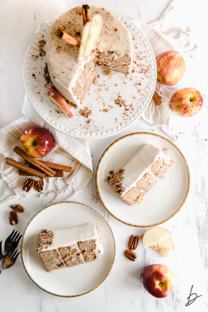 layer apple spice cake on cake plate next to two cake slices on white plates