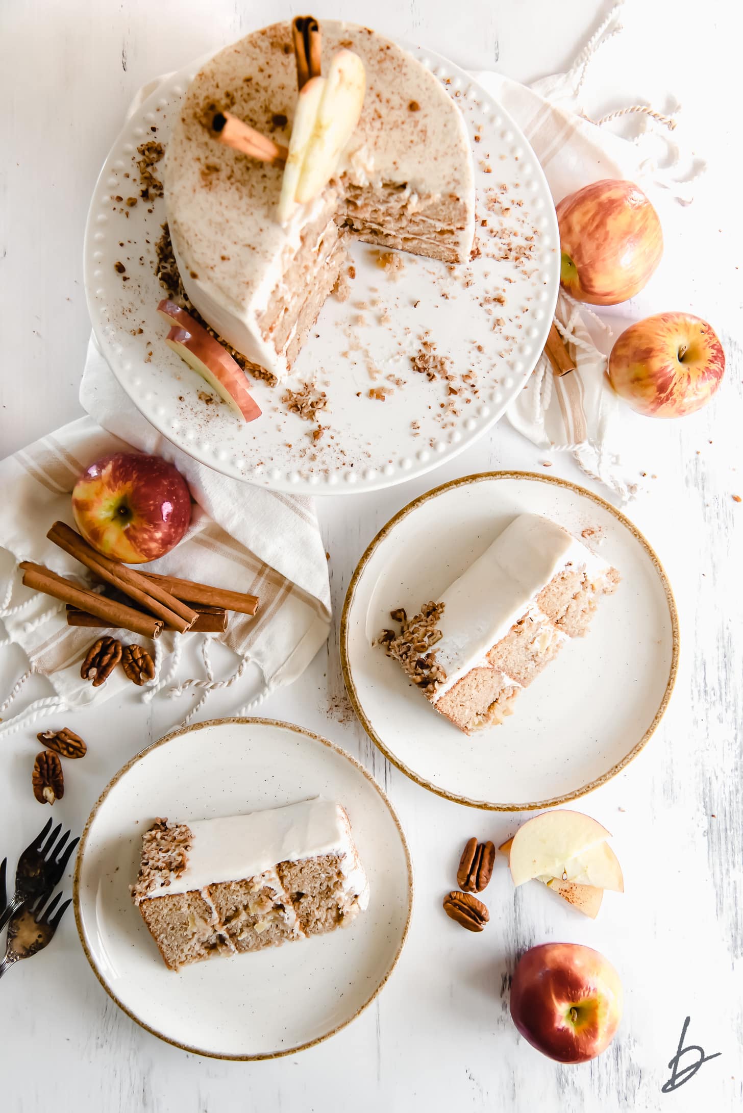 layer apple spice cake on cake plate next to two cake slices on white plates