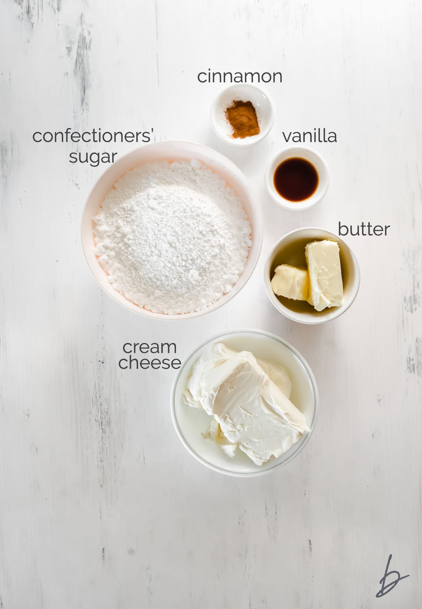 cinnamon cream cheese frosting ingredients in bowls labeled with text