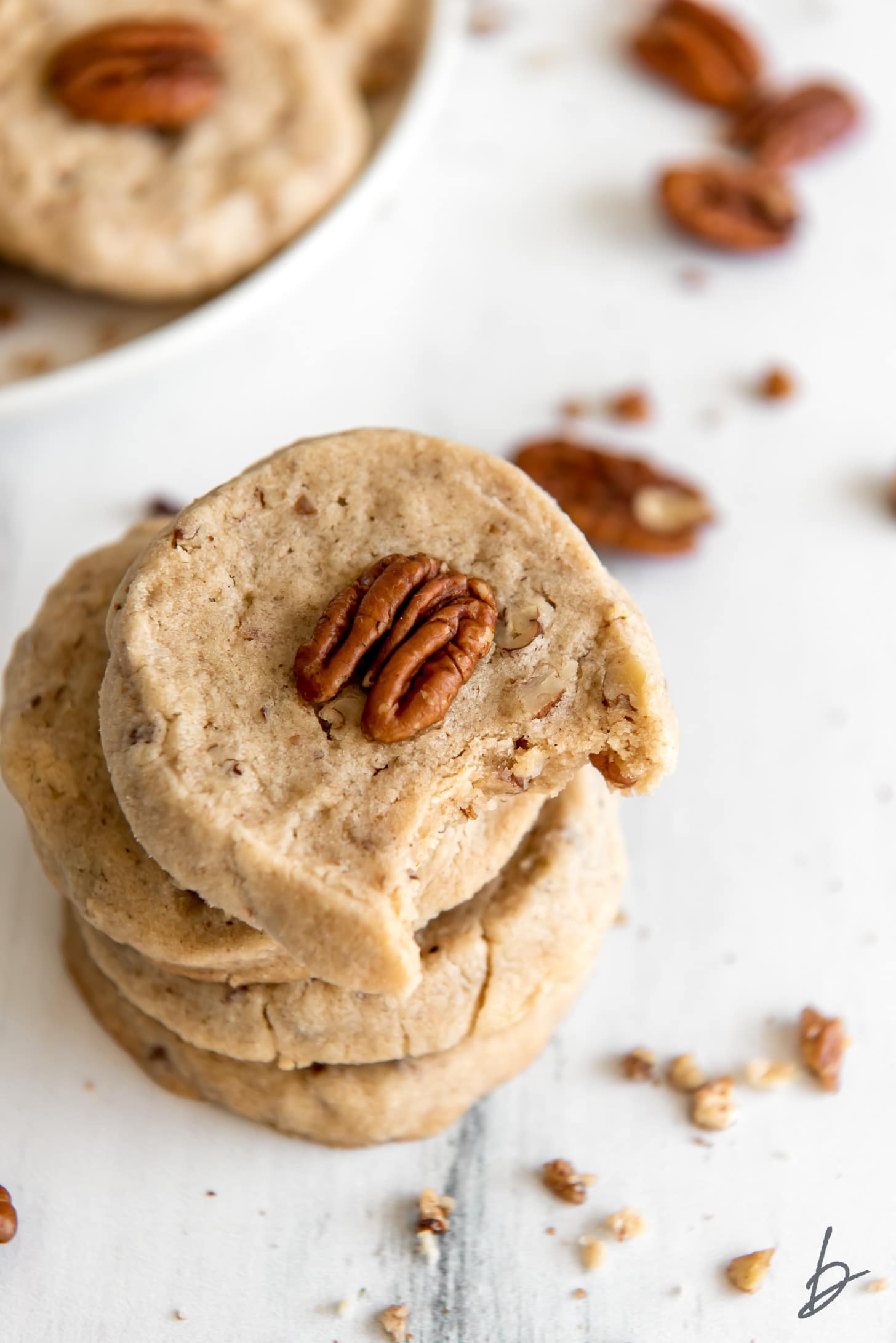 stack of pecan sandies and top cookie has a bite