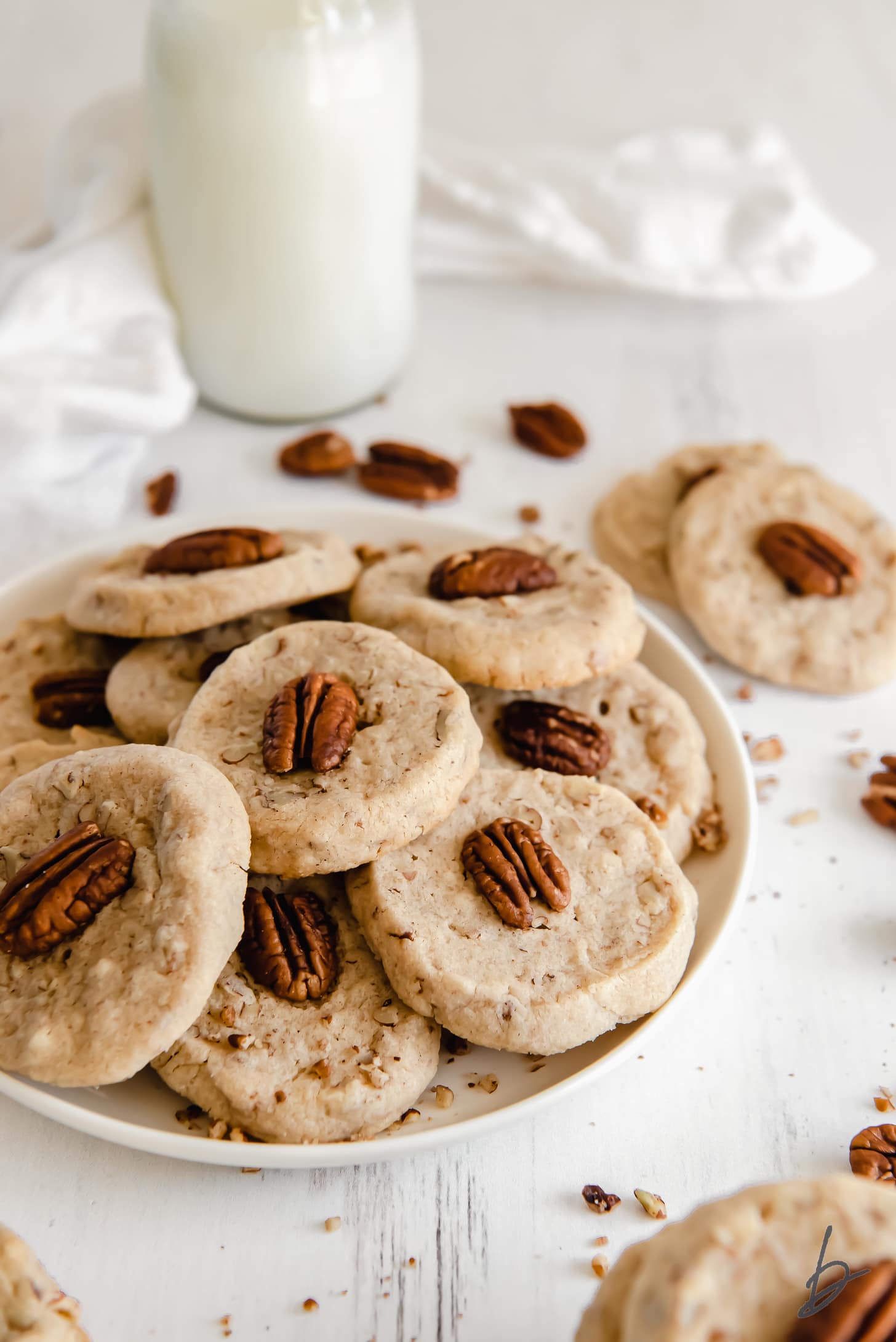 plate of pecan sandies cookies in front of a glass milk bottle