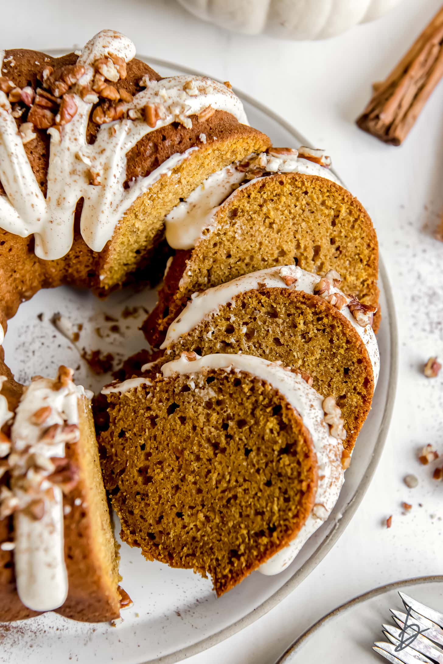 three slices of pumpkin bundt cake leaning up against bundt cake with cream cheese frosting