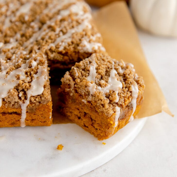 square slice of pumpkin coffee cake pulled away from rest of cake with streusel topping and icing
