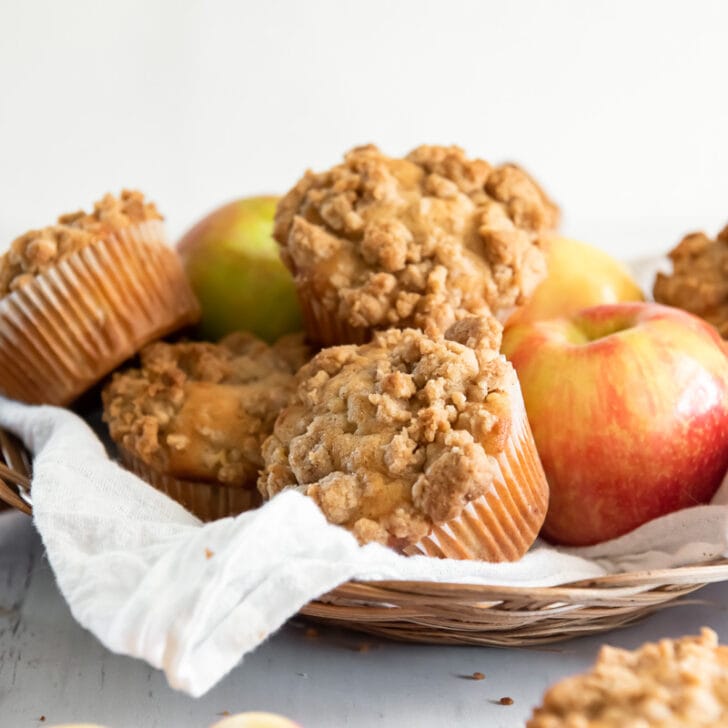 apple crumble muffins and honey crisp apples in a basket lined with parchment paper