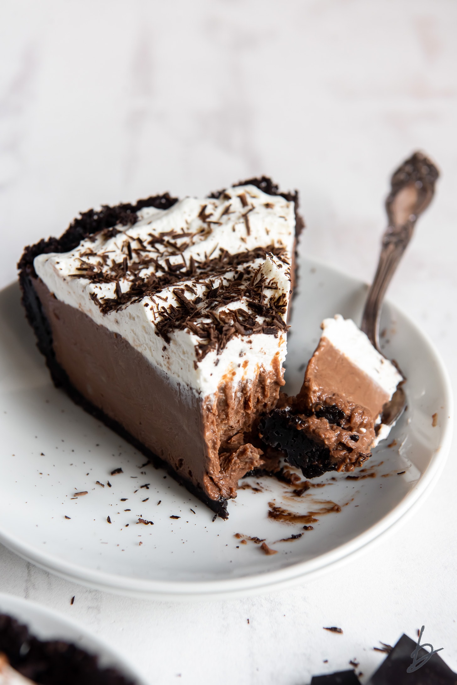 fork taking bite of chocolate cream pie with whipped cream and chocolate shavings