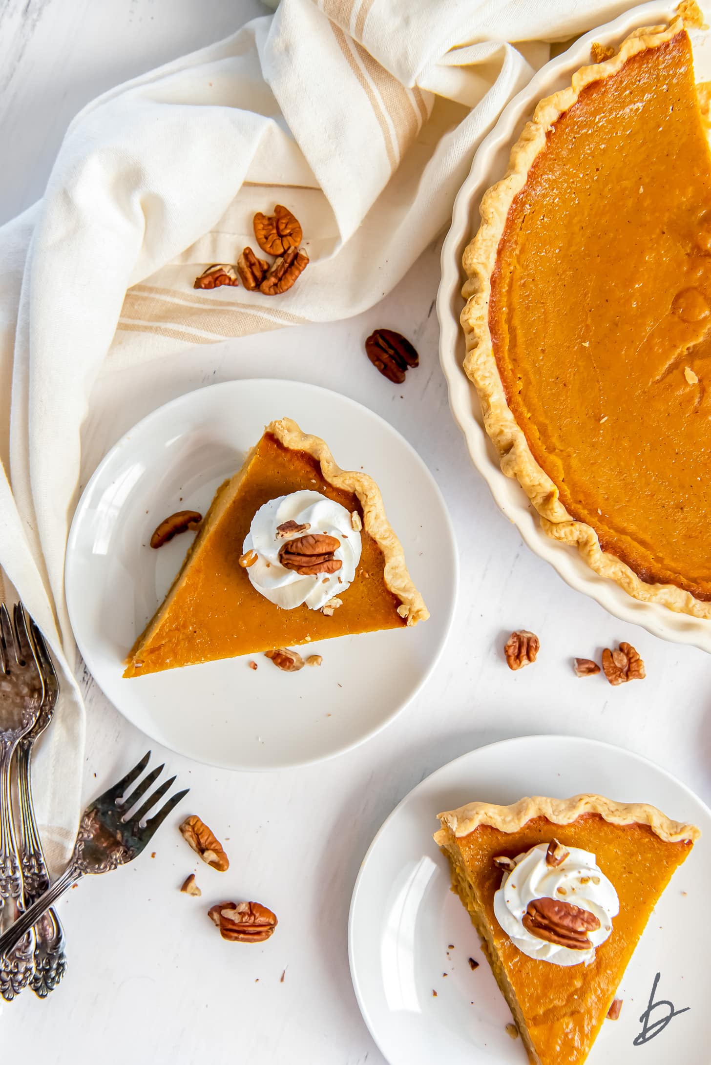 slices of sweet potato pie garnished with whipped cream and pecans on white round plates