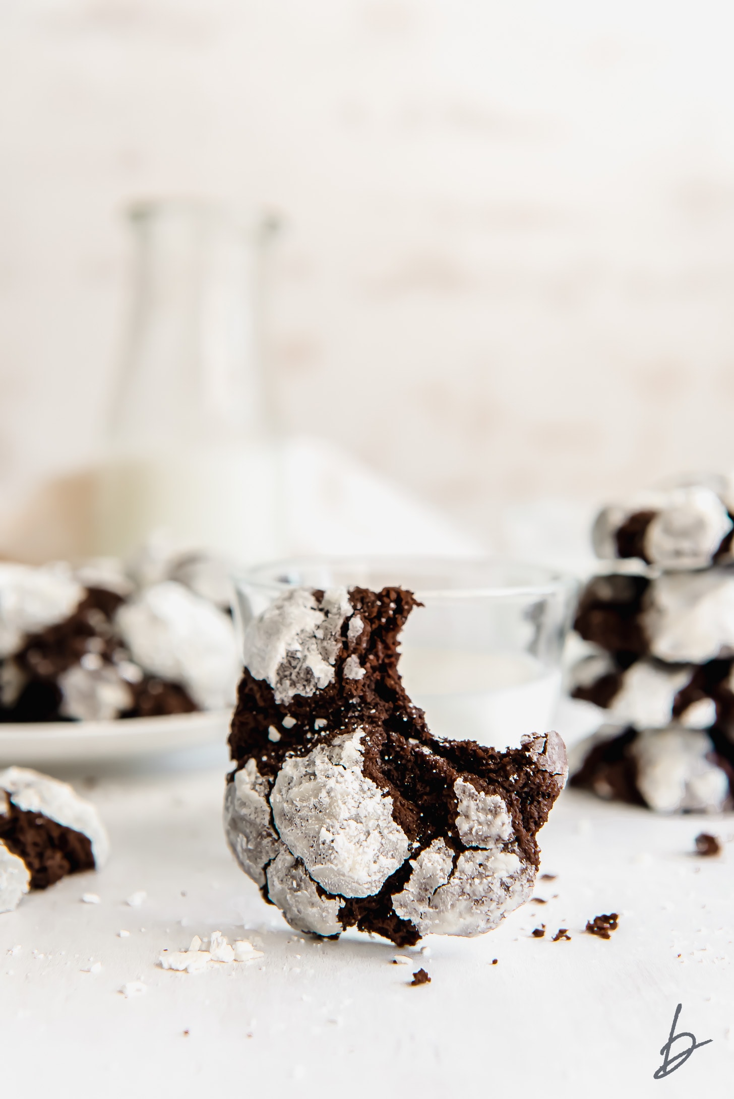 chocolate crinkle cookie with a bite leaning against glass of milk