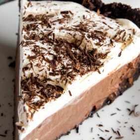 slice of chocolate cream pie topped with whipped cream and chocolate shavings