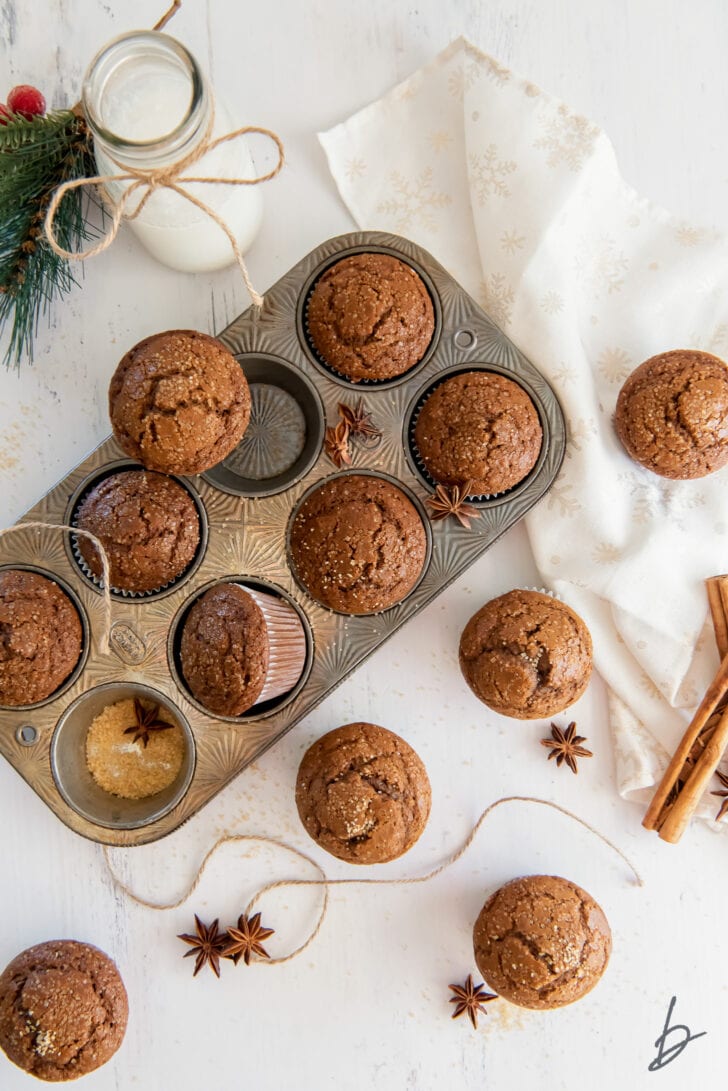 gingerbread muffins in an antique muffin pan next to more muffins, white kitchen cloth, cinnamon sticks and anise star