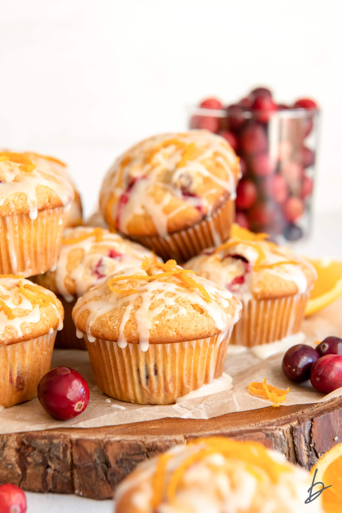cranberry orange muffins with glaze piled on wood tray
