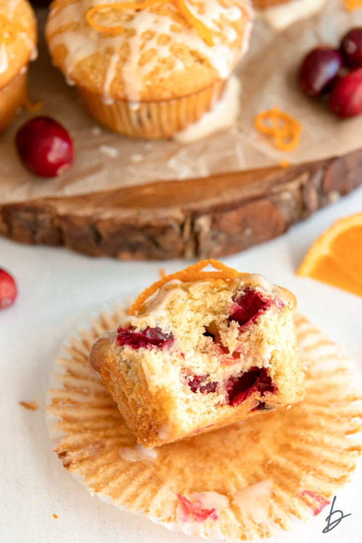 cranberry orange muffin with a bite on open paper muffin liner