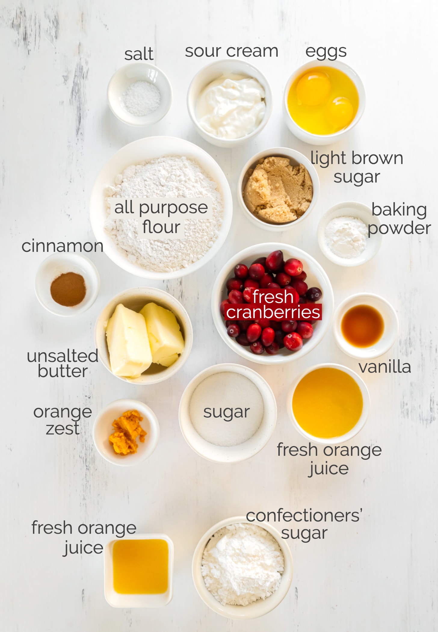 cranberry orange muffin ingredients in bowls labeled with text