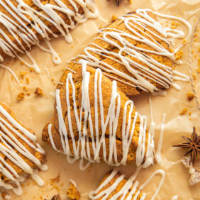 gingerbread scones with drizzle on parchment paper with anise star and candied ginger