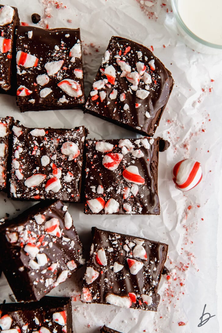 peppermint brownies topped with chocolate ganache and crushed candy canes on crumpled wax paper