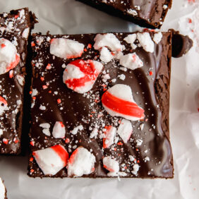 crushed peppermint on chocolate ganache peppermint brownie next to peppermint candy and another brownies