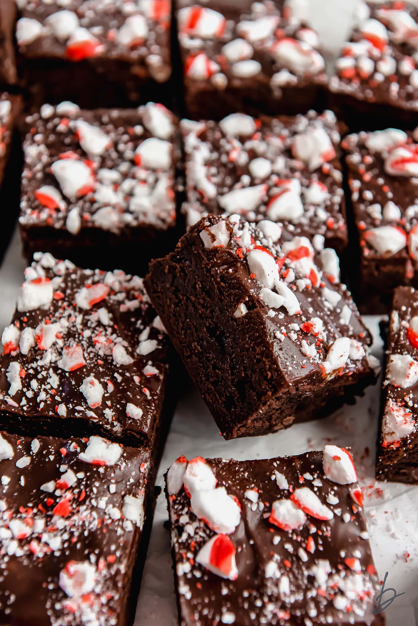 peppermint brownies turned on its side leaning up against more brownies with crushed peppermint on top