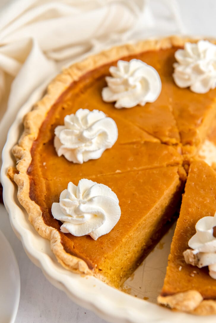 sweet potato pie slices garnished with whipped cream in pie dish