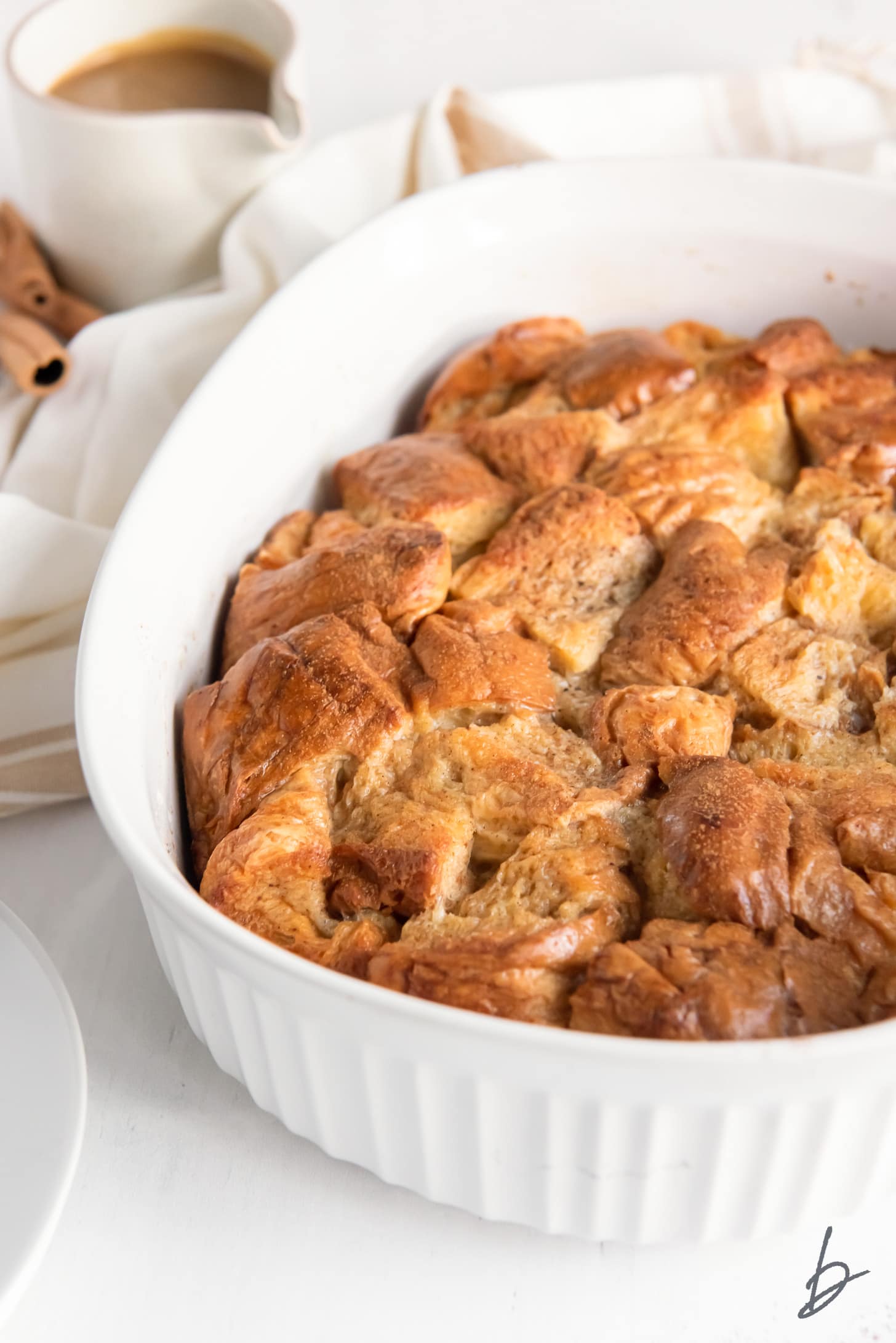 bread pudding with crispy golden top  in a white baking dish.
