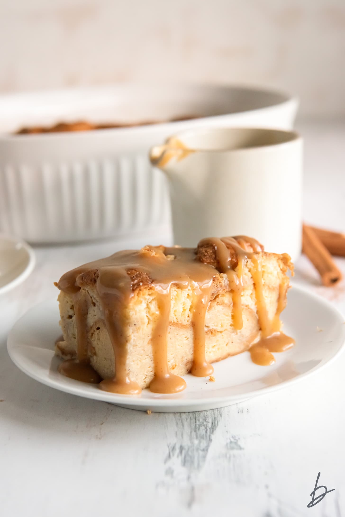 piece of bread pudding on a plate with bourbon sauce dripping down sides