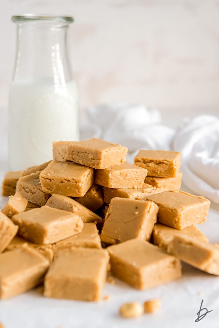 pile of peanut butter fudge squares in front of glass bottle of milk