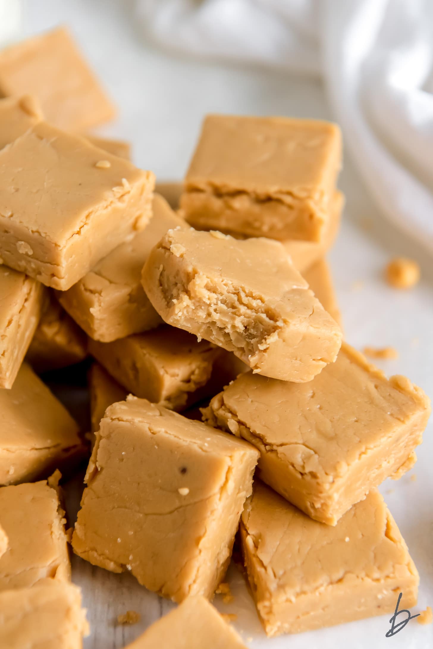 pile of peanut butter fudge and front piece has a bite from the corner