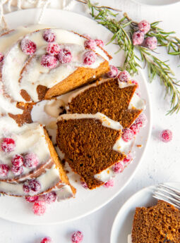 gingerbread bundt cake with cream cheese frosting with two slices cut and leaning against cake