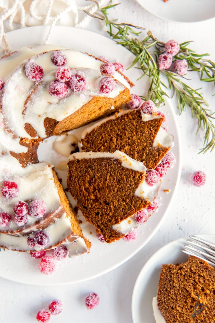 gingerbread bundt cake with cream cheese frosting with two slices cut and leaning against cake