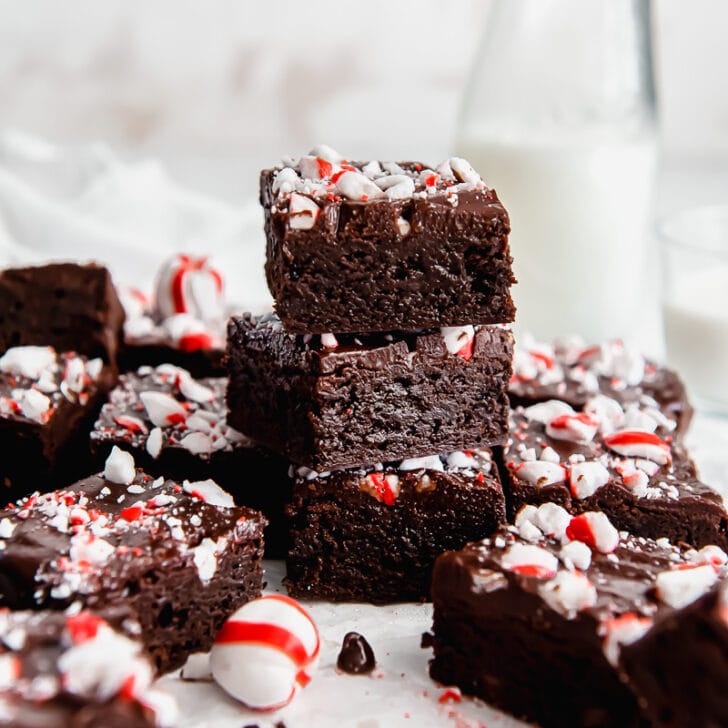 stack of fudgy peppermint brownies with crushed candy canes and chocolate ganache