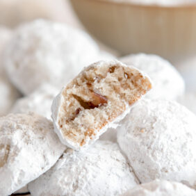 snowball cookie with a bite showing chopped pecans inside
