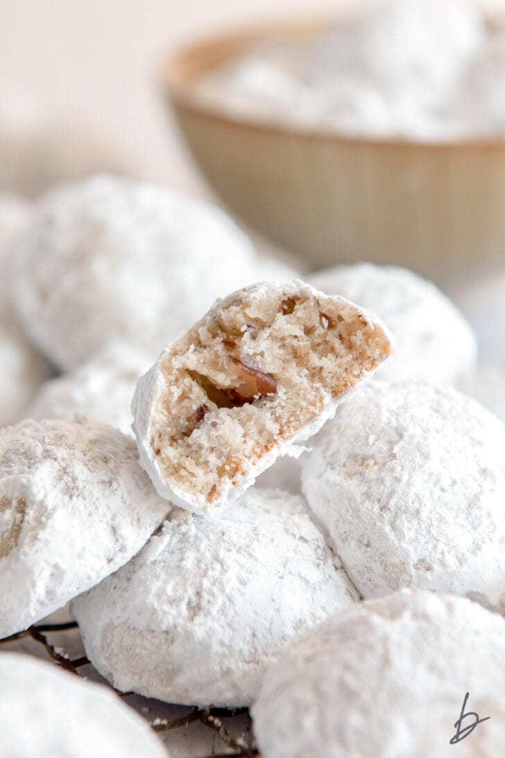 snowball cookie with a bite showing chopped pecans inside
