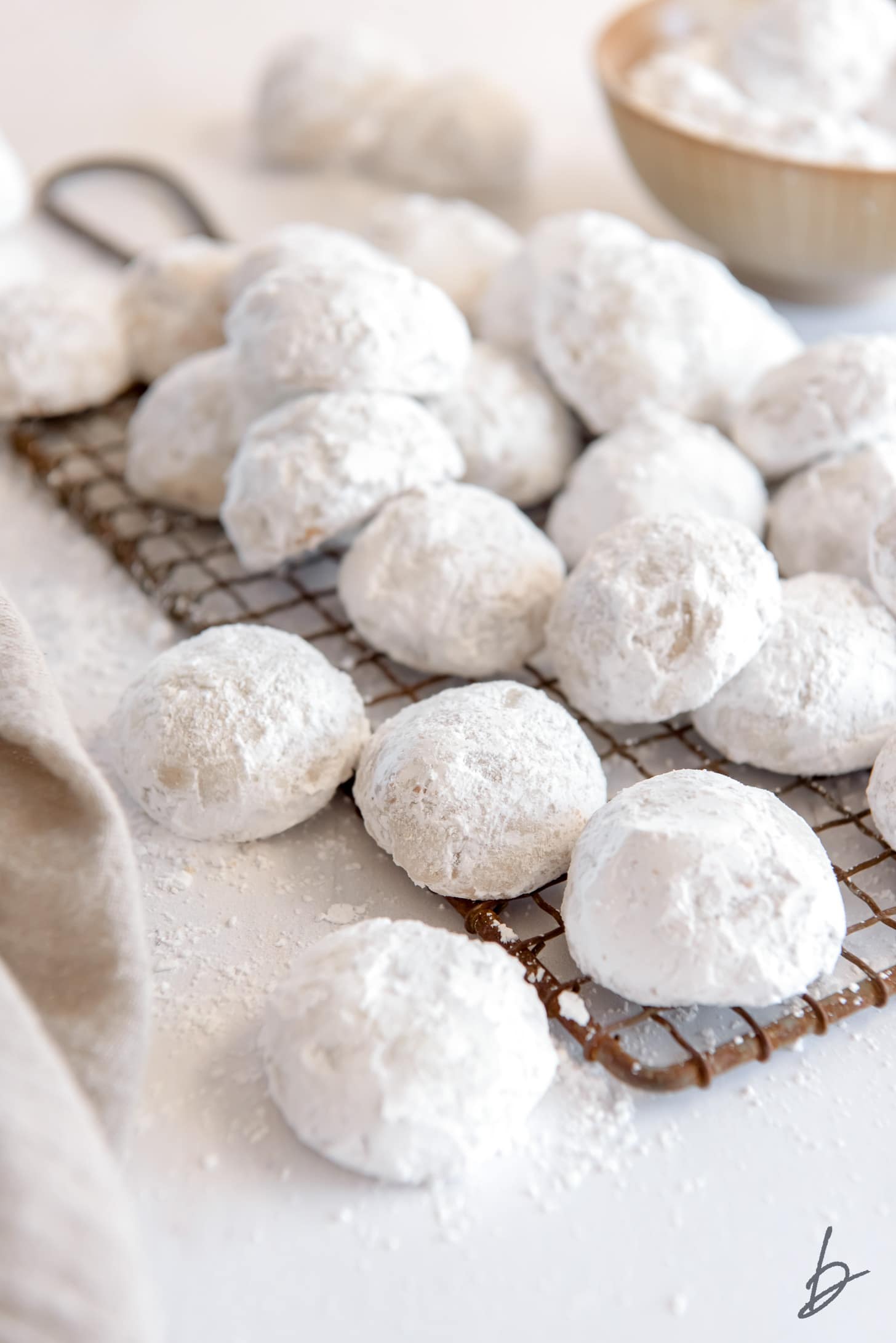 snowball cookies in a pile on small wire cooling rack