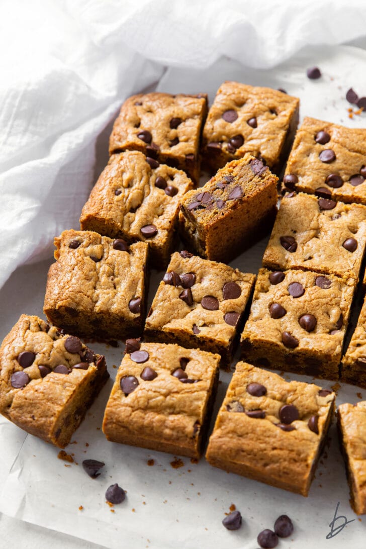 chocolate chip cookie bars cut into squares on white parchment paper