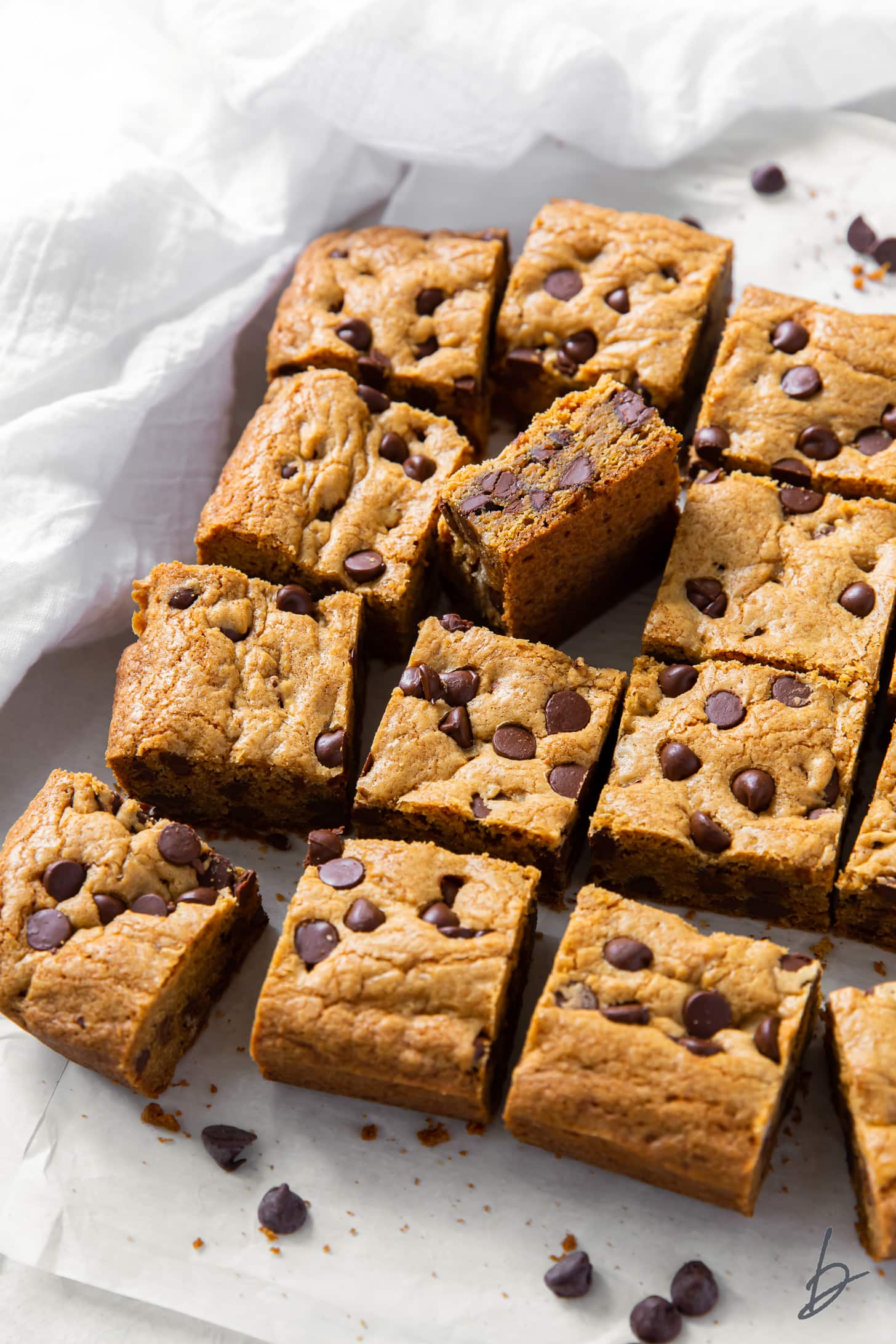 chocolate chip cookie bars cut into squares on white parchment paper.