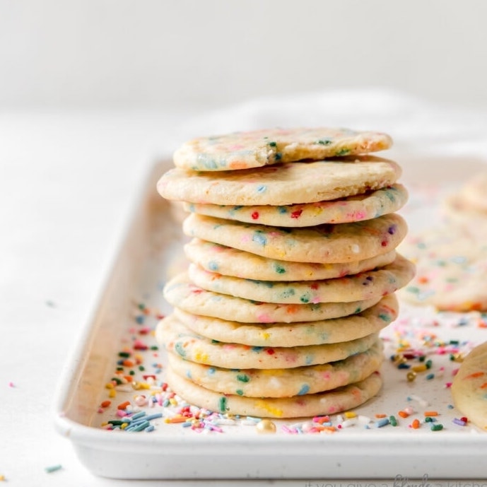 stackof sprinkle sugar cookies on a baking sheet