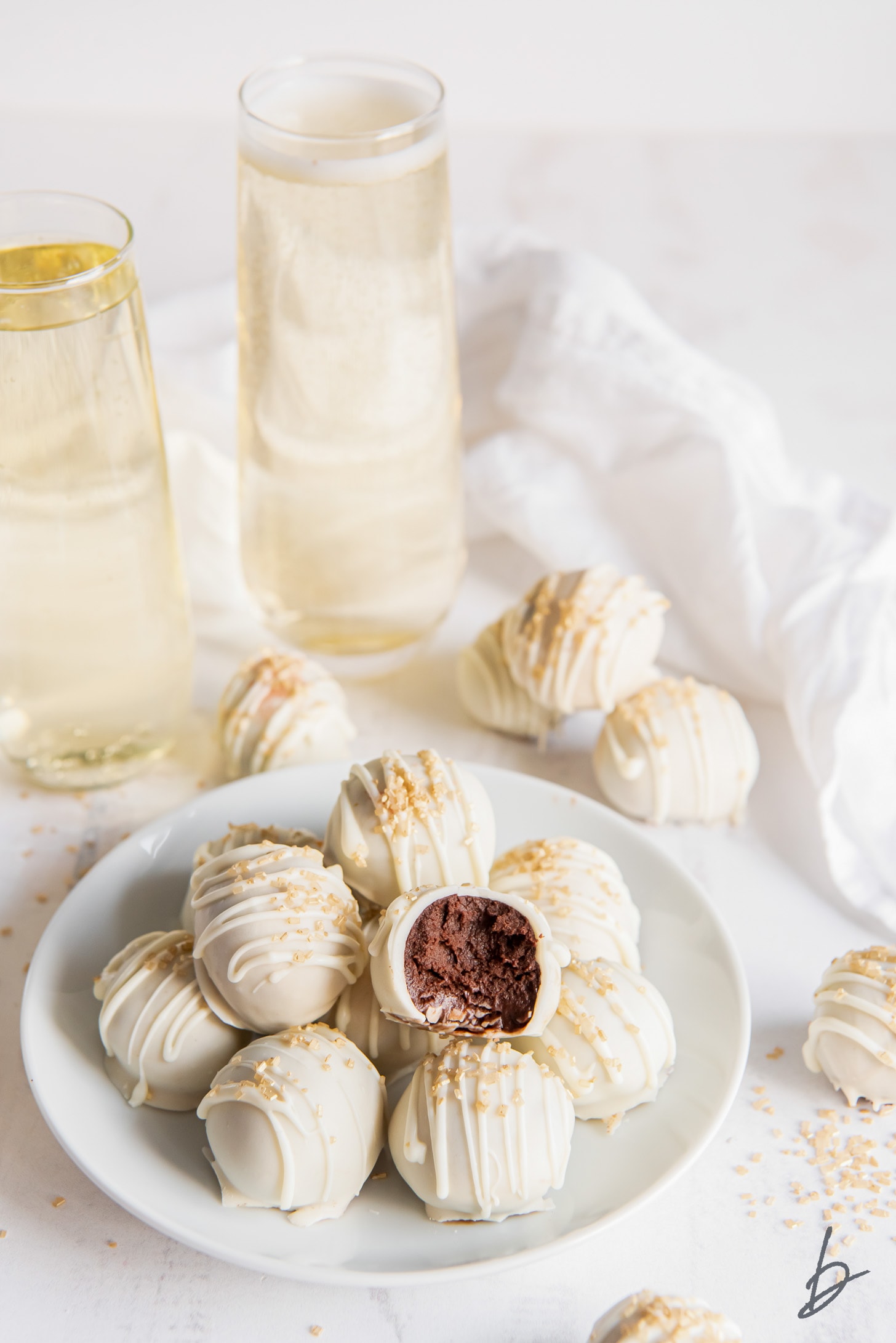 plate of champagne truffles and one truffles with a bite showing chocolate inside