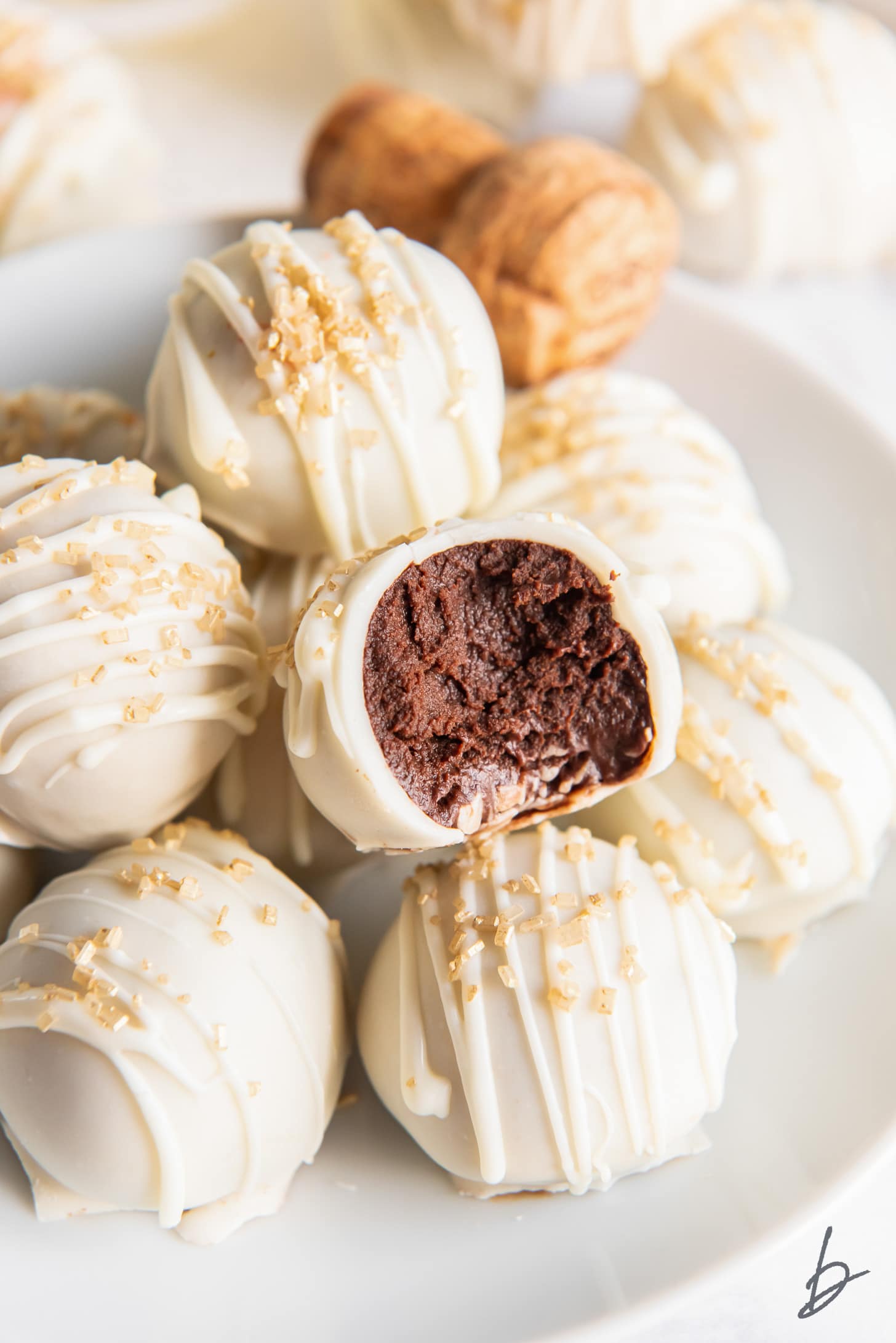 white chocolate covered champagne truffle with a bite showing chocolate inside