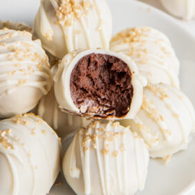 chocolate champagne truffle with a bite on top of more white chocolate covered truffles