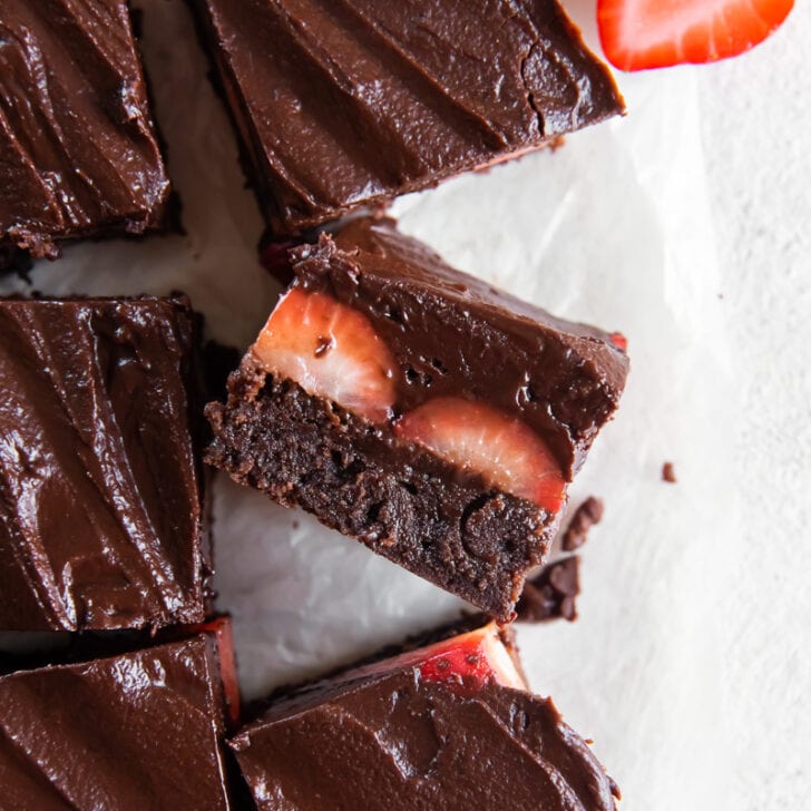 chocolate covered strawberry brownie on its side showing layers of brownies, strawberries and chocolate ganache